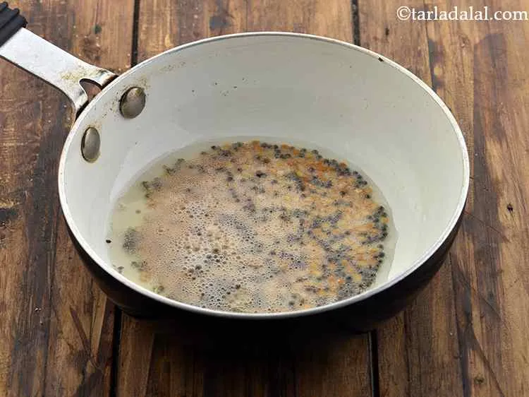 Step 9 – When the seeds crackle, add the cumin seeds and urad dal.