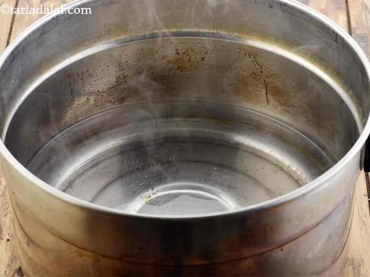 Step 15 – To make&nbsp;<strong>Sooji Idli</strong>, first heat water in a steamer or pressure cooker.