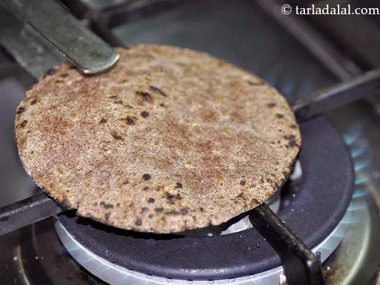 Step 27 – Now, place the bhakri on an open flame and with the help of tongs move …
