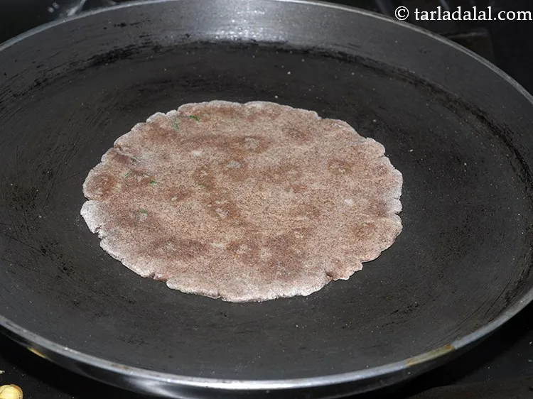 Step 16 – Heat a tava and place the rolled ragi roti carefully over it.