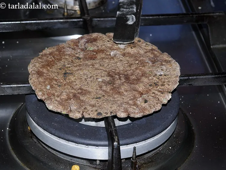 Step 19 – Lift the roti with a pair of flat tongs and roast over an open flame …