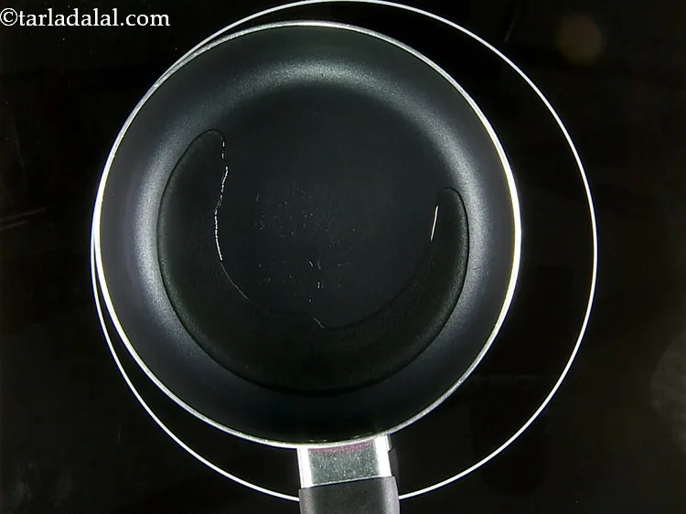 Step 26 – For the tempering of&nbsp;<strong>Rava Vegetable Dhoklas</strong>, heat the oil in a small pan.