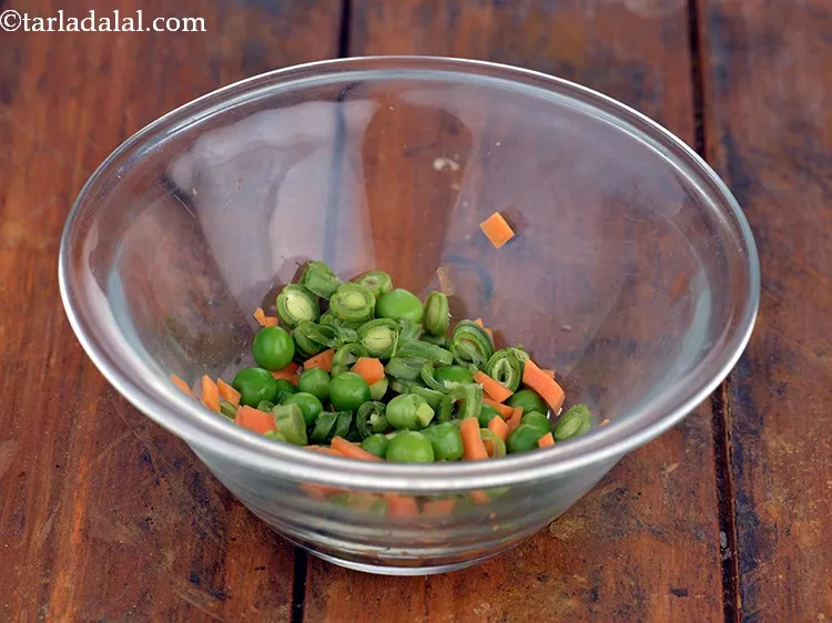 Step 3 – In a microwave safe bowl, take the carrots, French beans and some green peas.