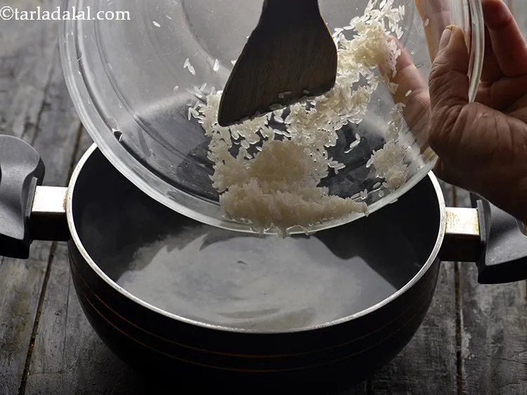 Step 14 – Add the washed and drained rice to boiling water and mix well using a wooden …