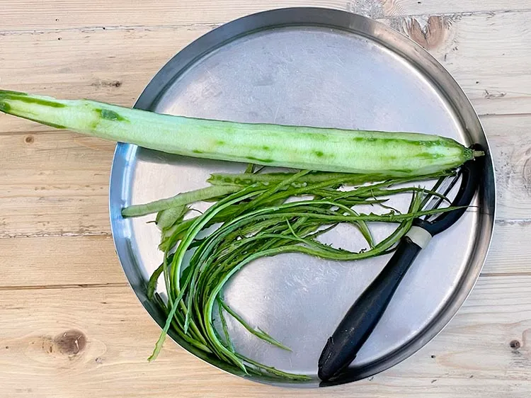 Step 3 – Wash and peel the ridge gourd.