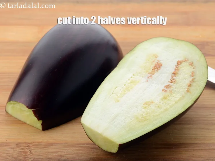 Step 7 – Place the brinjal on a chopping board and cut into 2 halves vertically.&nbsp;