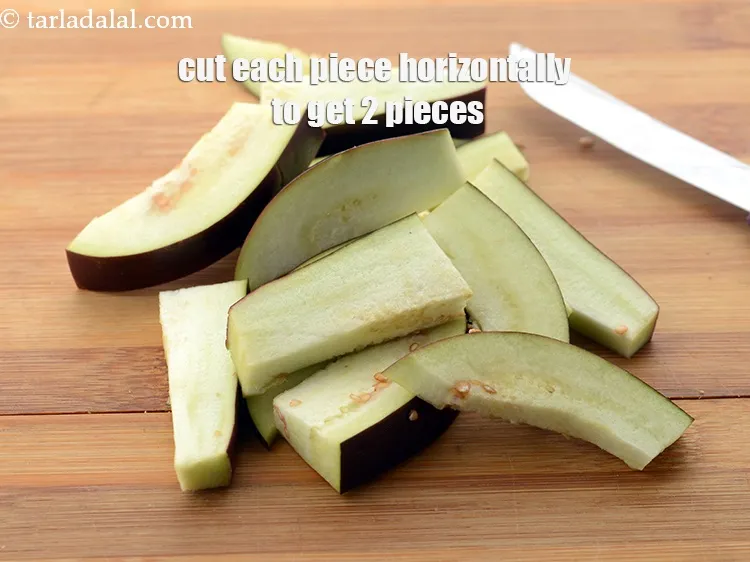 Step 9 – Cut each piece horizontally to get 2 pieces, this is called sliced brinjal. Keep aside.&nbsp;