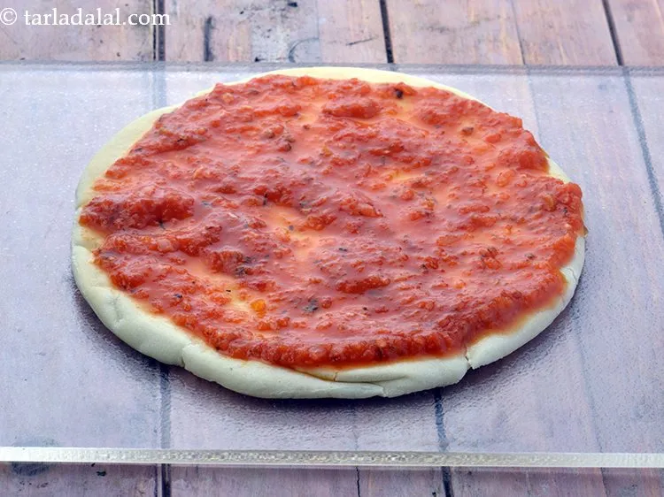 Step 28 – Spread &frac14; cup&nbsp;<a href="https://www.tarladalal.com/pizza-sauce-399r">pizza sauce</a> evenly over it.