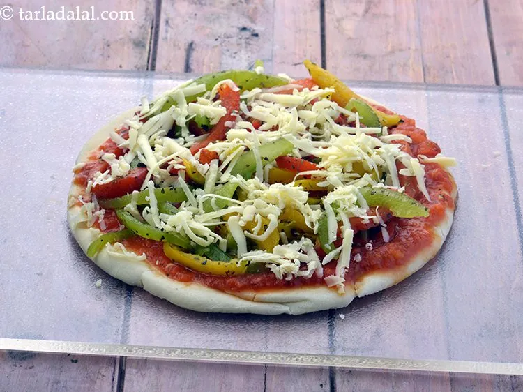 Step 30 – Finally sprinkle &frac14; cup of <a href="https://www.tarladalal.com/glossary-grated-mozzarella-cheese-1022i">grated mozzarella cheese</a>&nbsp;evenly over it.