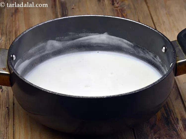 Step 6 – Add the remaining 2&frac14; cups of <a href="https://www.tarladalal.com/glossary-milk-514i">milk</a>&nbsp;in a deep non-stick pan and boil on …