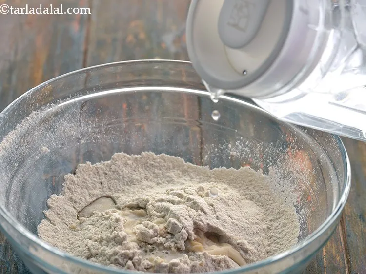 स्टेप 10 – आटा बनाने के लिए धीरे-धीरे पानी डालें।