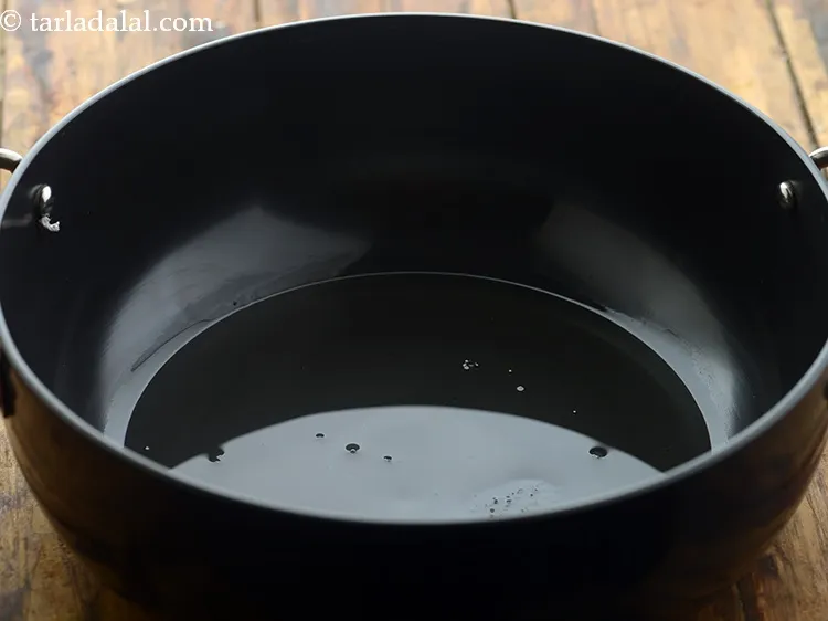 Step 4 – To make coconut kadhi for <strong>kadhi samosa chaat</strong>, heat oil in a kadhai.&nbsp;