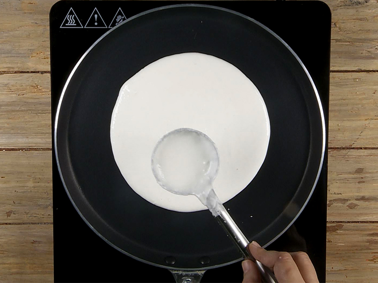 Step 6 – Spread the dosa batter in a circular motion using a deep spoon to make a …
