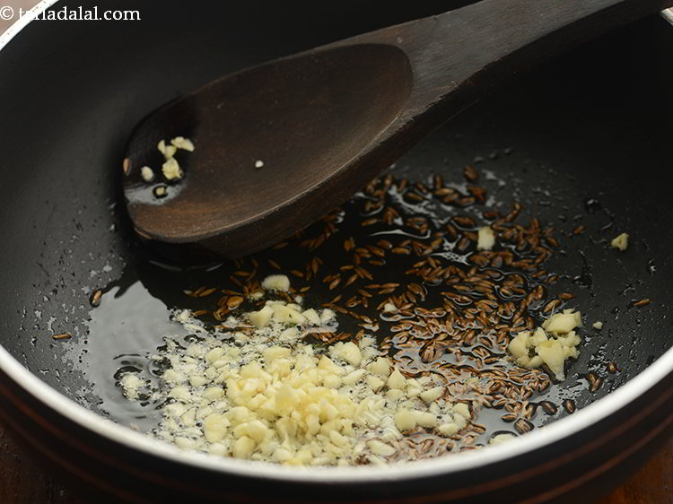 Step 19 – When the seeds crackle, add garlic.