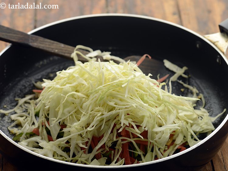 स्टेप 27 – पत्तागोभी डालें। मसालेदार शेजवान नूडल्स को कुरकुरा बनाने के लिए …