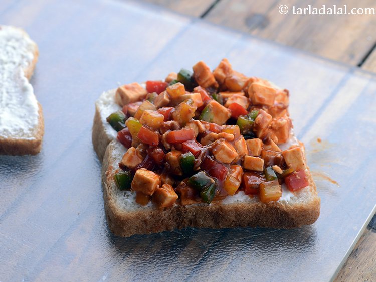 स्टेप 15 – एक ब्रेड स्लाइस पर समान रूप से पनीर सेज़वान भरवां …