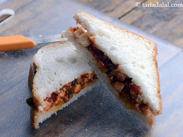 स्टेप 17 – <strong>पनीर सेज़वान सैंडविच</strong> को तिरछे २ बराबर टुकड़ों में काट …