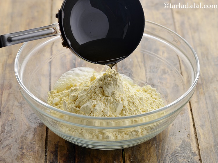 Step 3 – Add the hot oil. This provides a crumbly texture to the <strong>besan sev</strong>.