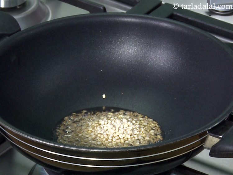Step 11 – <div> When the seeds crackle, add the urad dal.</div>