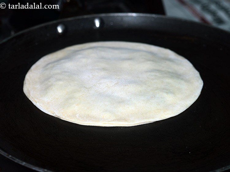 Step 19 – Heat a non-stick tava (griddle), place the paratha on it.