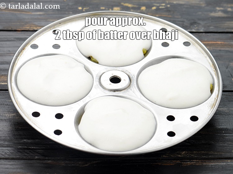 Step 21 – Pour approx. 2 tbsp of the idli batter over the bhaji in each mould.
