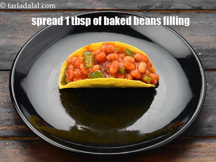 Step 22 – Spread 1 tbsp of the&nbsp;<a href="https://www.tarladalal.com/glossary-baked-beans-177i">baked beans</a>&nbsp;filling in it.&nbsp;