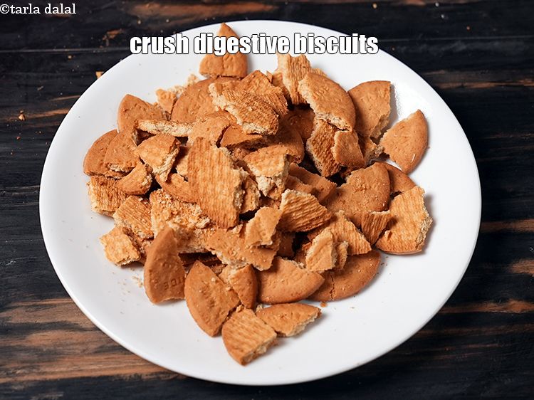 Step 4 – To <strong>mini mango cheesecake recipe</strong>, crush 20 <a href="https://www.tarladalal.com/glossary-digestive-biscuit-207i">digestive biscuits</a> in a big bowl.