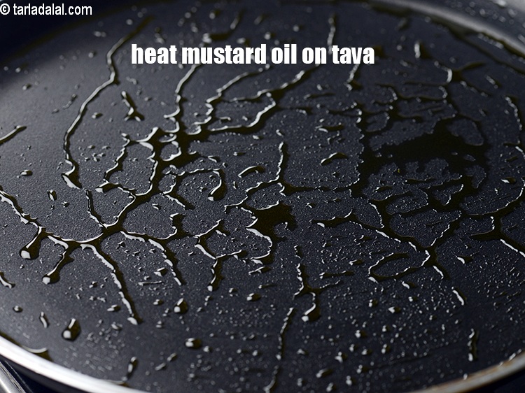 Step 3 – Heat 1 tsp of mustard oil on a tava.&nbsp;