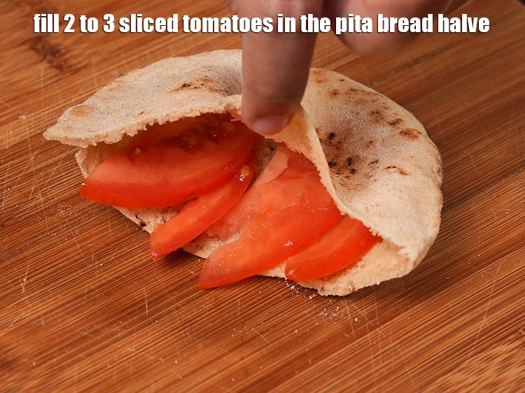 Step 32 – Fill 2 to 3 <a href="https://www.tarladalal.com/glossary-sliced-tomatoes-746i">sliced tomatoes</a> in the&nbsp;pita bread halve.