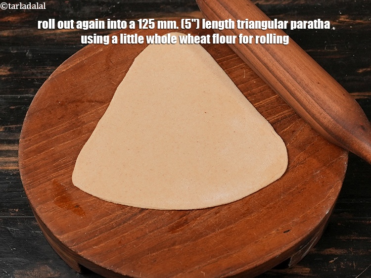 Step 15 – Roll out again into a 125 mm. (5&quot;) length triangular paratha using a little whole …
