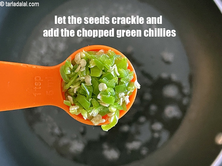 Step 25 – When the seeds crackle, add &nbsp;<strong>1 1/2 tsp</strong>&nbsp;<a href="glossary-chopped-green-chilli-820i">chopped green chillies</a>.