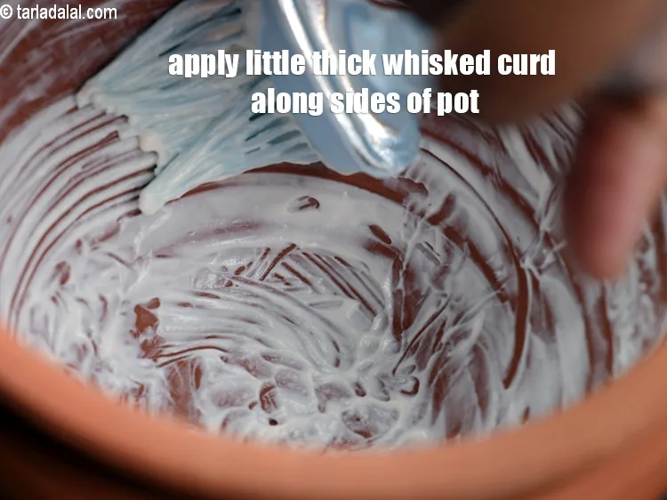 Step 13 – Meanwhile apply little thick whisked curd along the sides of the earthen pot using a …