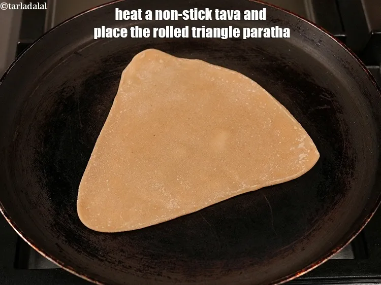 Step 16 – Heat a non-stick tava (griddle) and place the rolled triangle paratha.