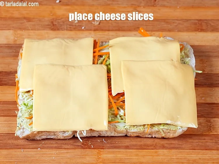 Step 16 – Place 4 <a href="https://www.tarladalal.com/glossary-cheese-slices-765i">cheese slices</a> evenly over it.