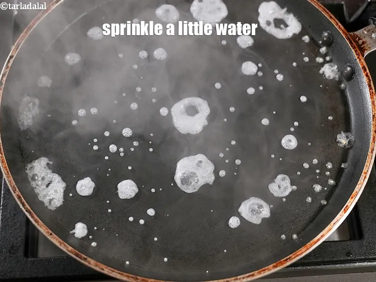 Step 13 – Sprinkle a little water on the tava (griddle).