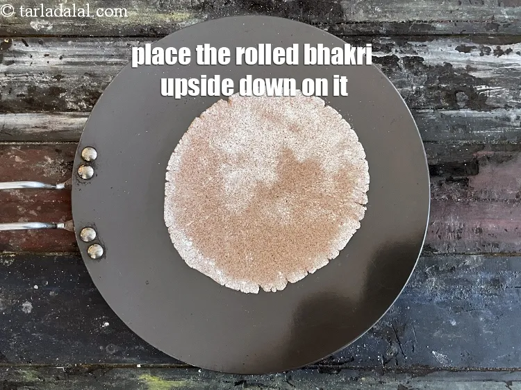 Step 14 – Place the rolled bhakri dough upside down on it.