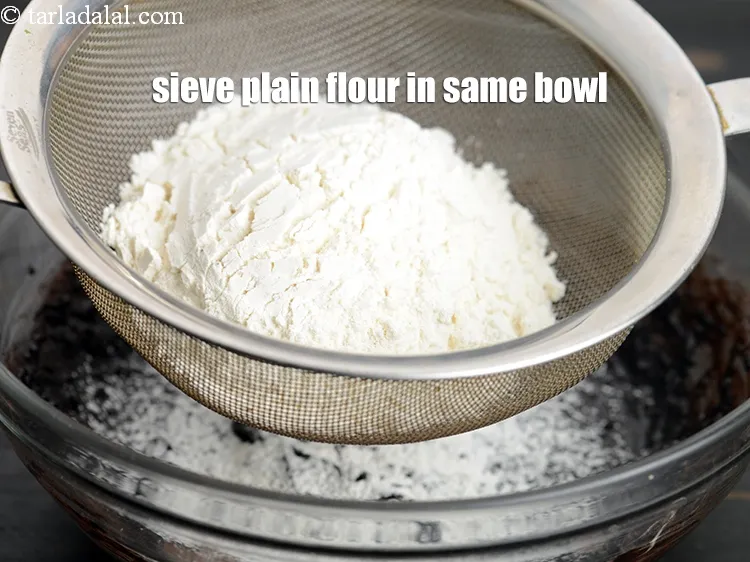 Step 13 – Sieve 1/2&nbsp;cup <a href="https://www.tarladalal.com/glossary-plain-flour-maida-188i">plain flour (maida)</a>, in the same bowl.