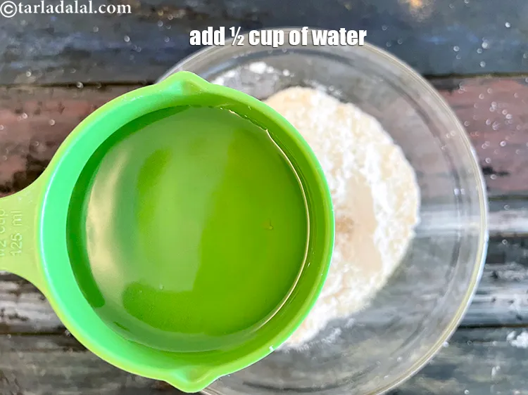 स्टेप 14 – आटा गूंथने के लिए पर्याप्त पानी डालें।&nbsp;हमने 1/2 कप पानी …
