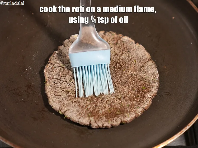 Step 14 – Cook the roti on a medium flame, using &frac14; tsp of oil.