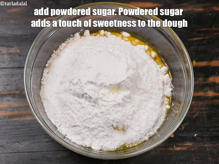 स्टेप 14 – १/२ कप&nbsp;<a href=""https://www.tarladalal.com/glossary-powdered-sugar-hindi-280i"">पिसी हुई चीनी</a>&nbsp;डालें&nbsp;। पिसी चीनी आटे में थोड़ी …