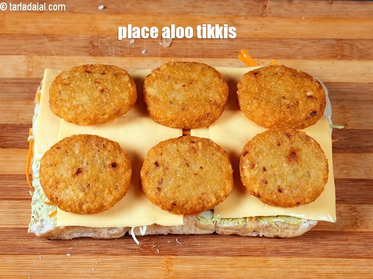 Step 17 – Place 6 <a href="https://www.tarladalal.com/aloo-tikkis-32745r">aloo tikkis</a> over the cheese slices.