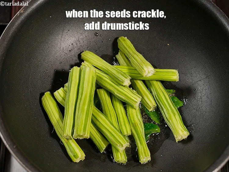 Step 14 – When the seeds crackle, add 1 cup <a href="https://www.tarladalal.com/glossary-drumstick-saijan-ki-phalli-395i">drumsticks (saijan ki phalli / saragavo)</a>.&nbsp;