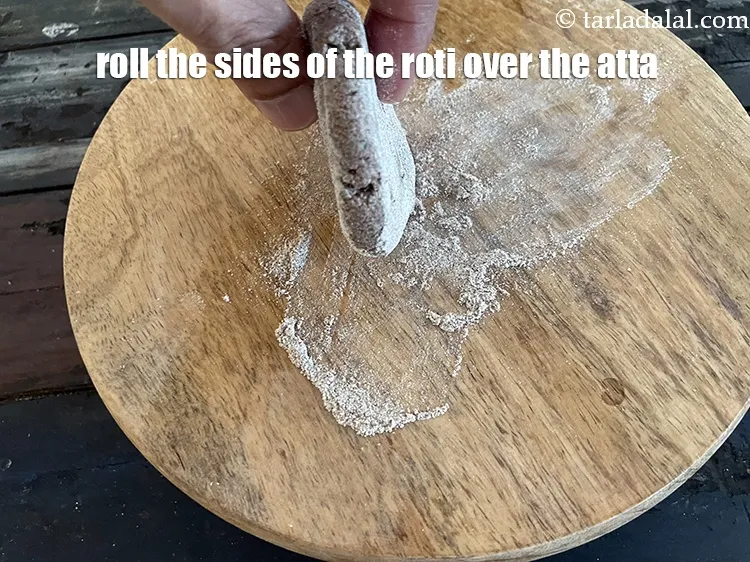 Step 31 – To get atta on the sides of the roti, hold it vertically and gently roll …
