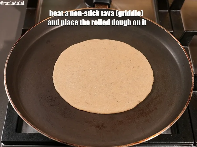 Step 15 – <meta charset="UTF-8" />Heat a non-stick tava (griddle) and place the rolled dough on it.