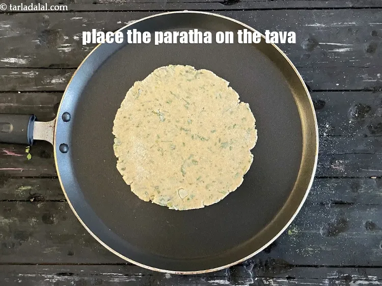 Step 15 – <meta charset="UTF-8" />Place the paratha gently on the tava.&nbsp;&nbsp;