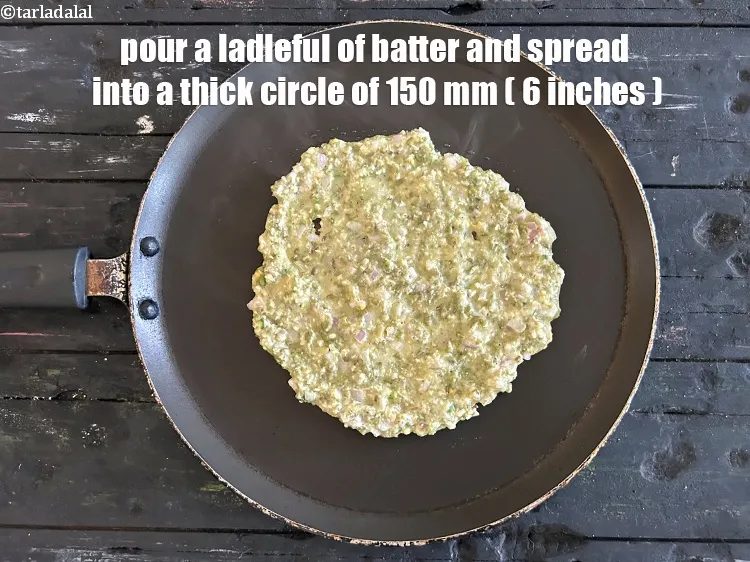 Step 17 – Pour a ladleful of the batter on the tava (griddle) and spread it evenly to …