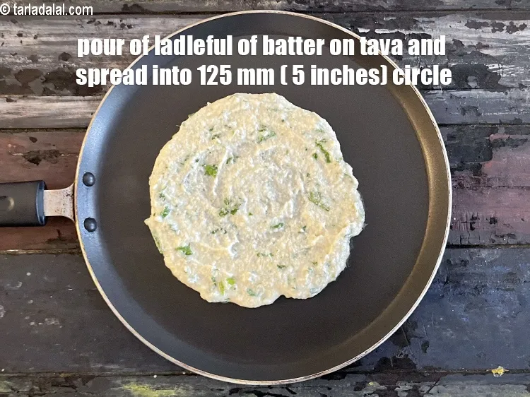 Step 28 – <meta charset="UTF-8" /> Pour a ladleful of the batter on the tava (griddle) and spread …