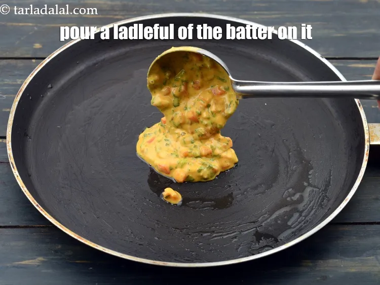 Step 16 – Pour a ladleful of the batter on the tava (griddle).