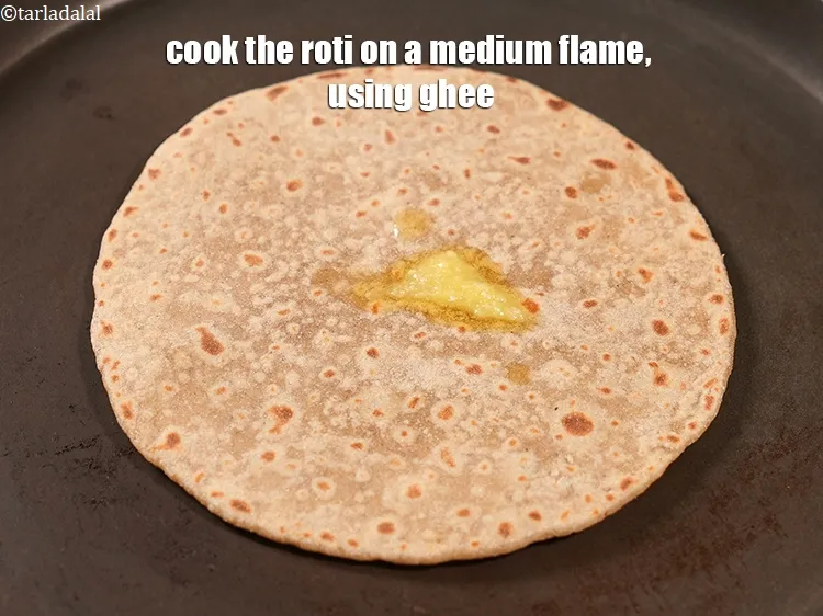 Step 16 – Cook the roti on a medium flame, using 4 tsp&nbsp;<a href="https://www.tarladalal.com/glossary-ghee-245i">ghee</a>.