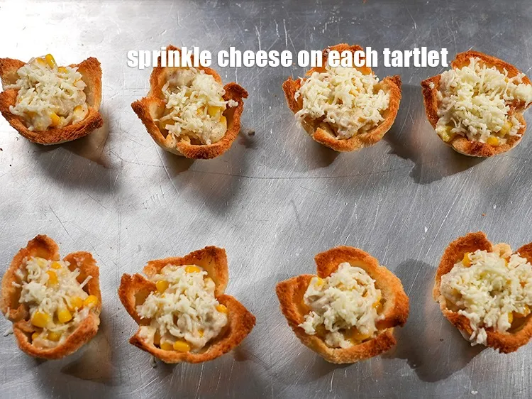 स्टेप 22 – प्रत्येक टार्टलेट पर &frac12; टेबल-स्पून&nbsp;<a href=""https://www.tarladalal.com/glossary-grated-processed-cheese-hindi-868i"">कसा हुआ प्रोसेस्ड चीज़</a>&nbsp;छिड़कें।